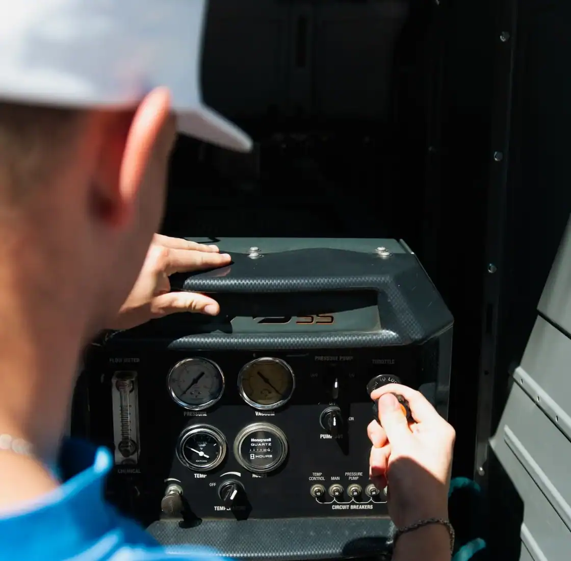 Technician adjusting pressure and temperature controls on the truck mount unit