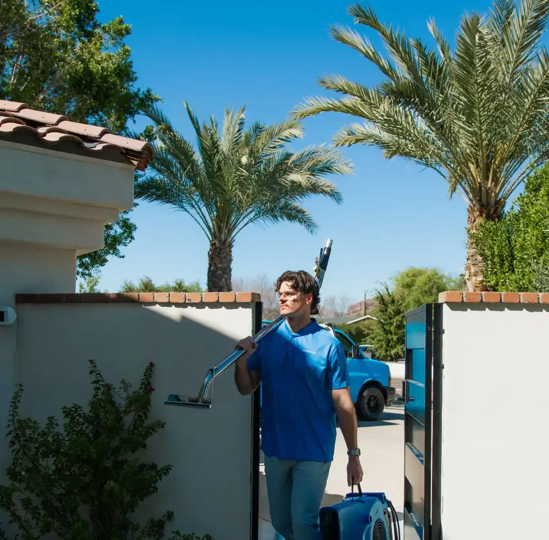 Coconut Cleaning technician arriving through a garden gate with an extraction wand