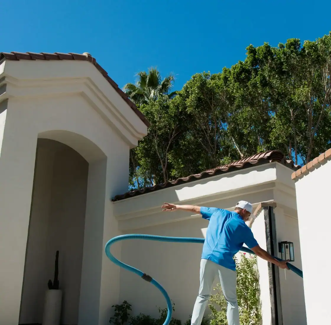 Coconut Cleaning technician bringing the cleaning hose to a front door