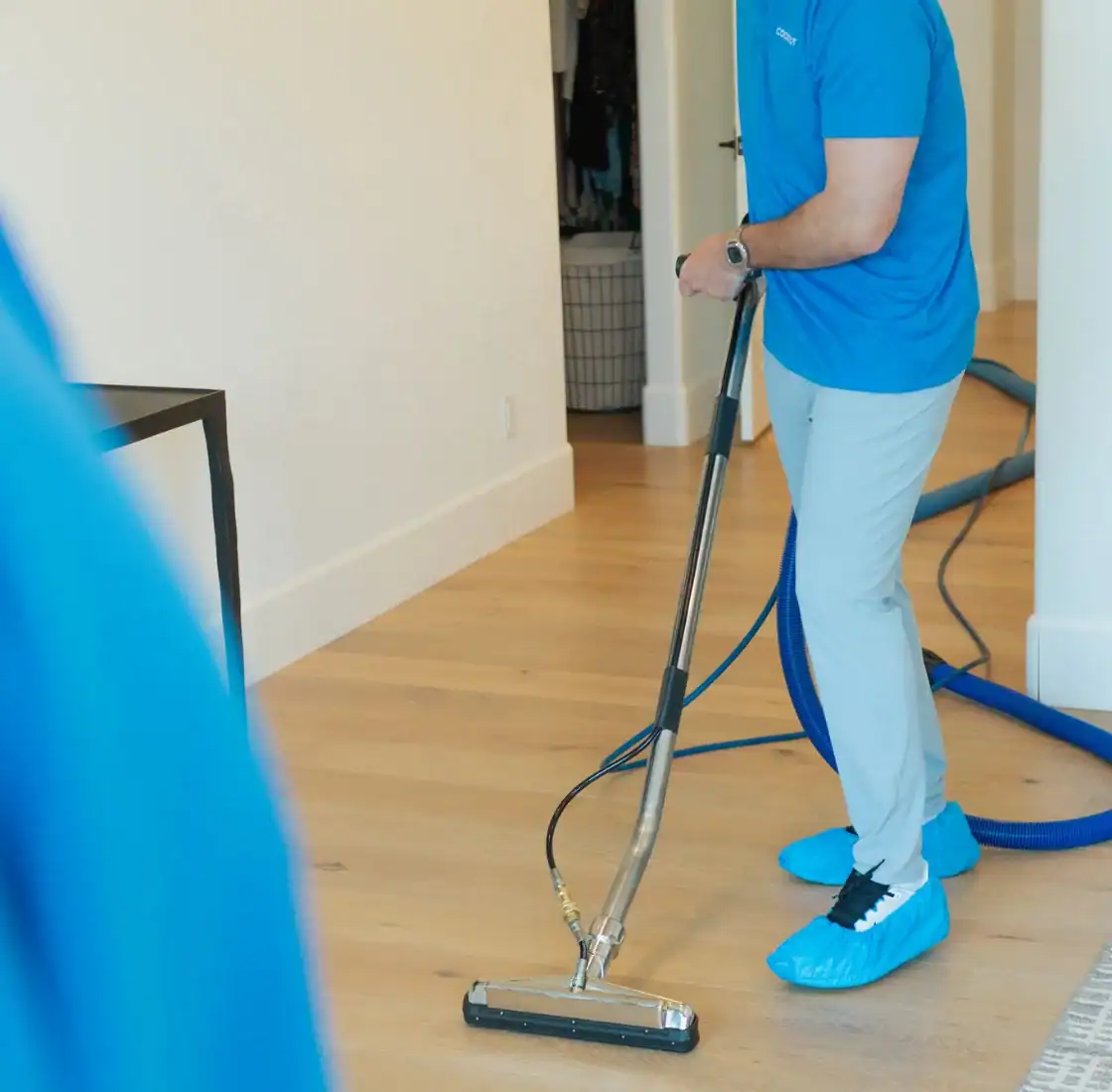 Coconut Cleaning technician cleaning carpet near a home entryway with an extraction wand
