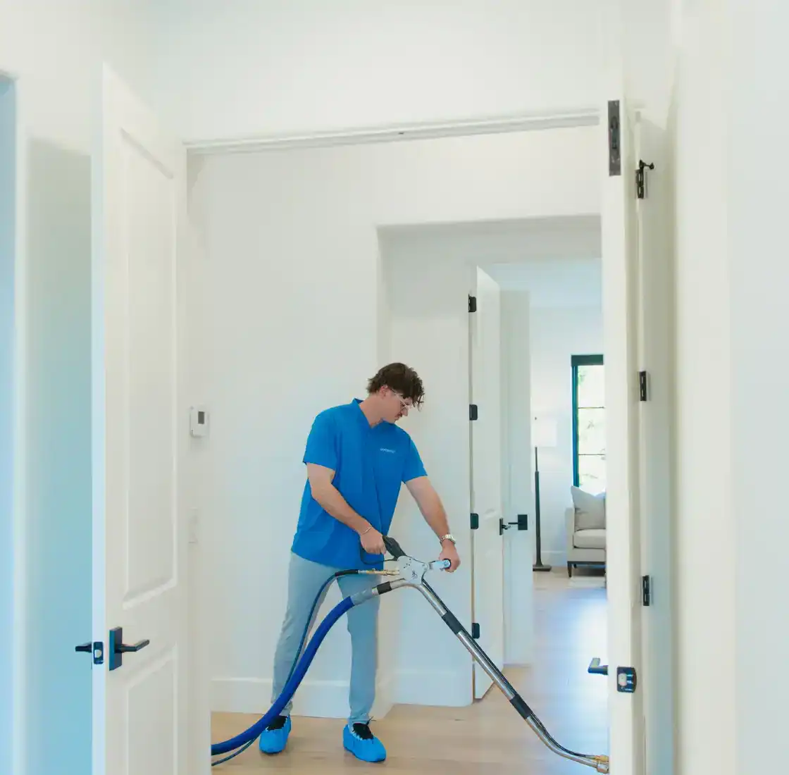 Coconut Cleaning technician cleaning carpet along a home hallway with an extraction wand