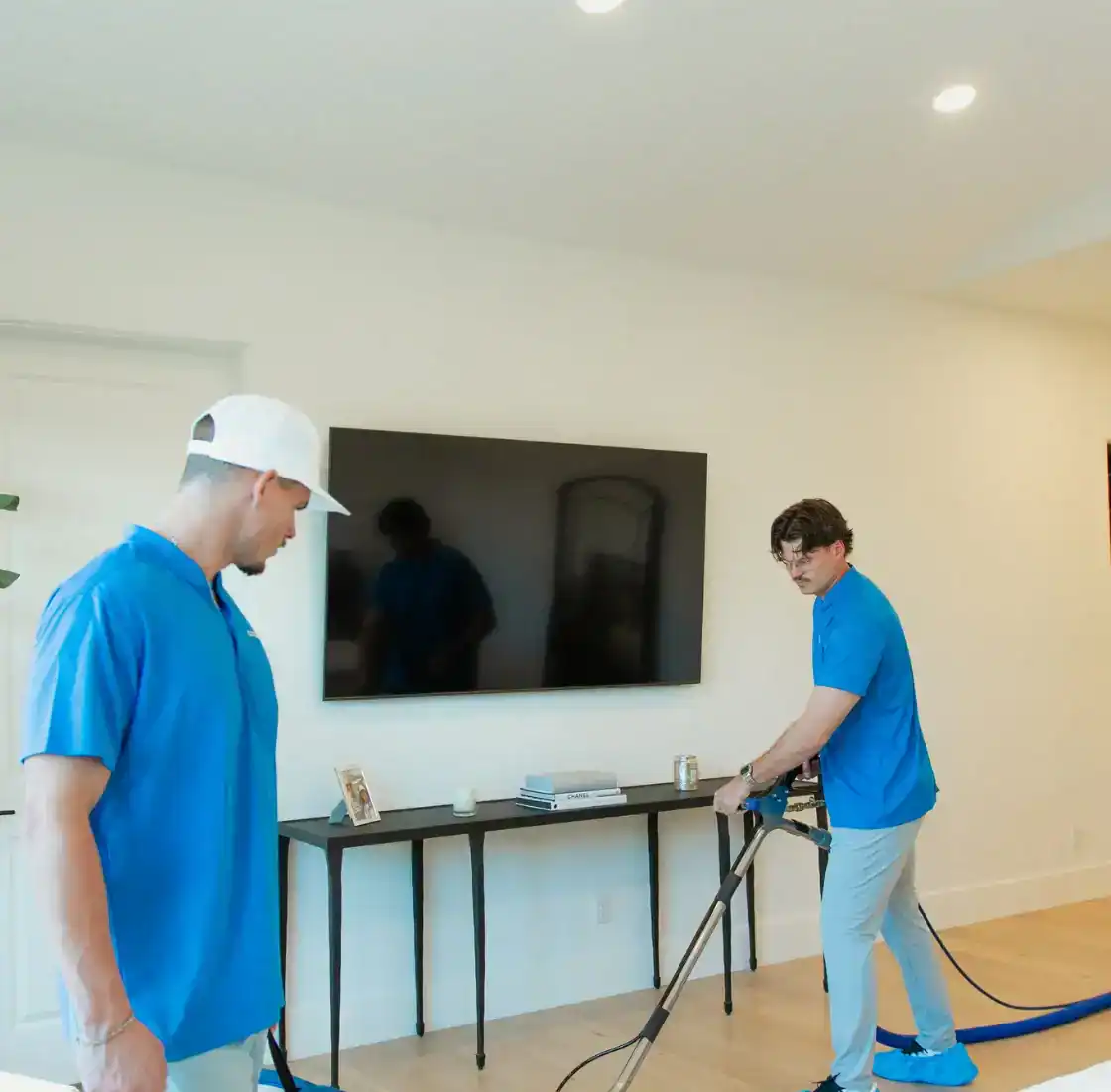Two Coconut Cleaning technicians cleaning carpet in an open living room