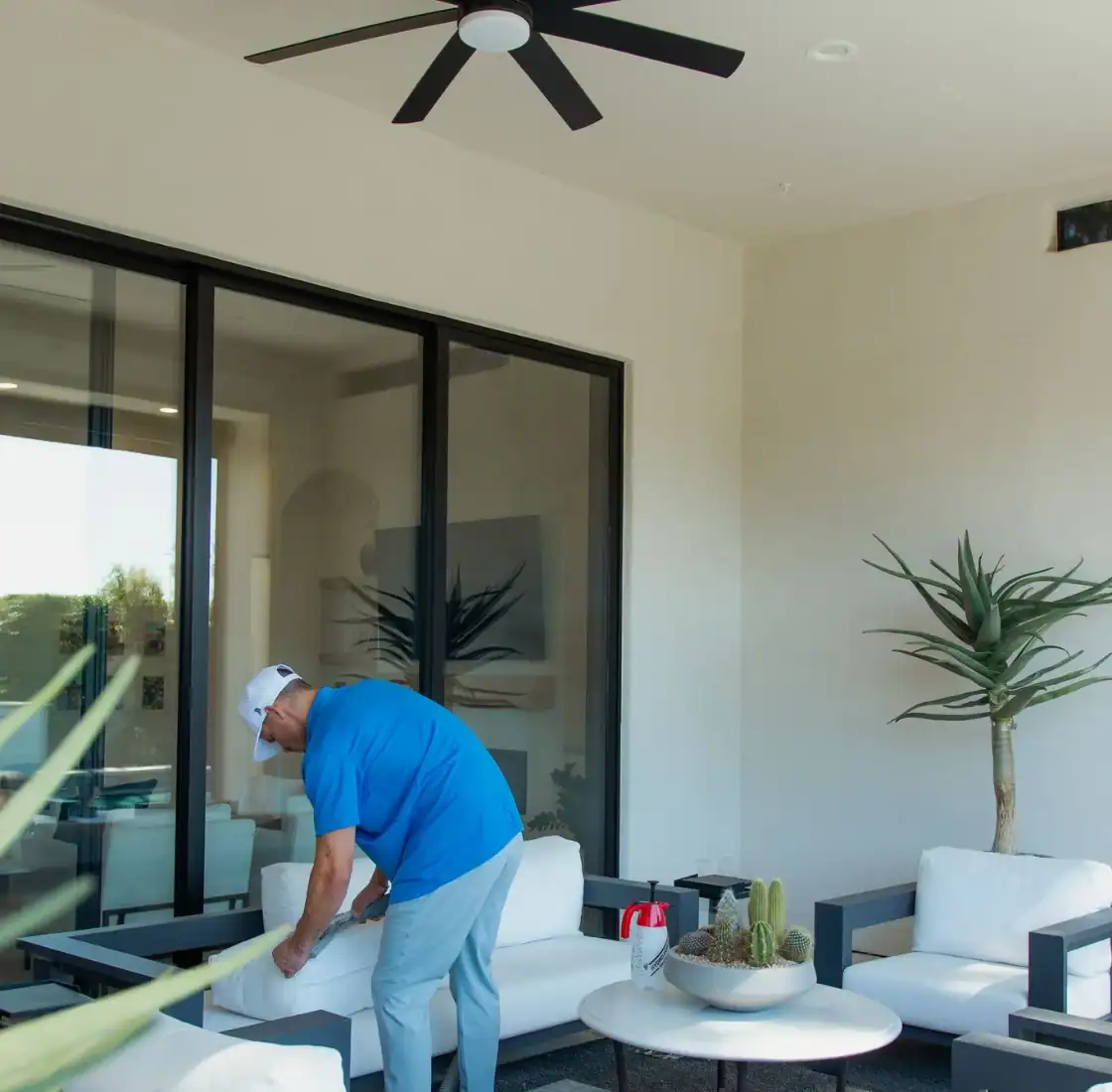 Technician cleaning patio furniture on a covered poolside terrace