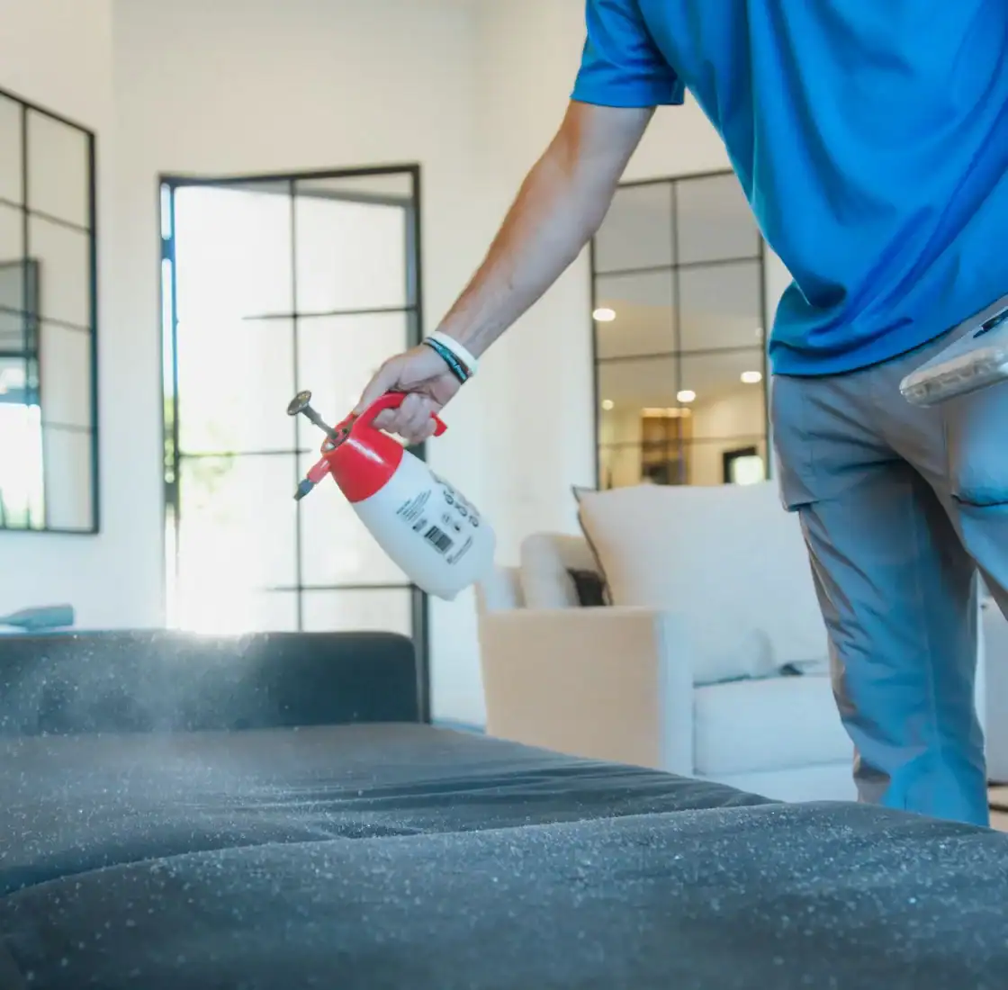 Technician spraying pre treatment onto a sofa before cleaning
