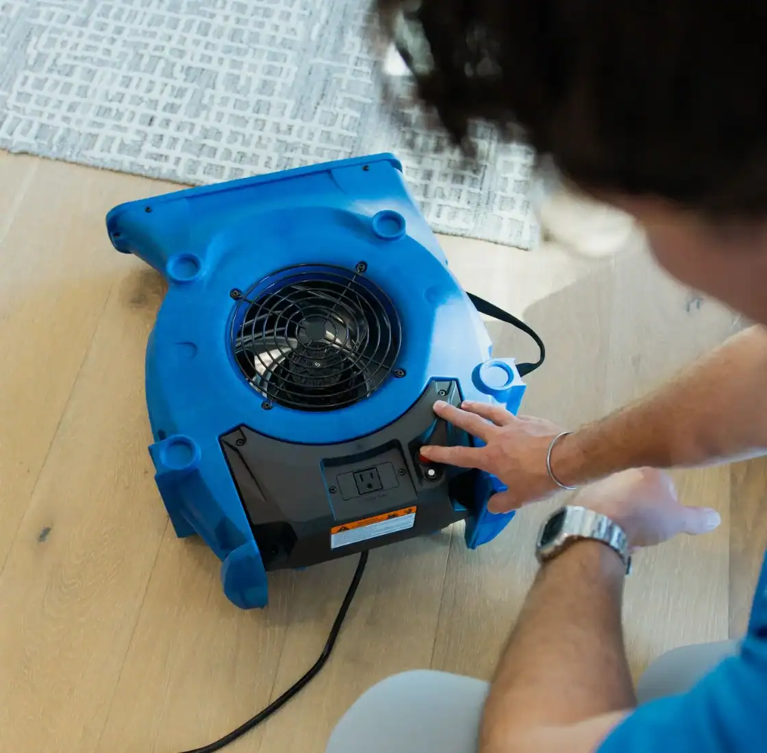 Technician setting down an air mover to dry a freshly cleaned floor