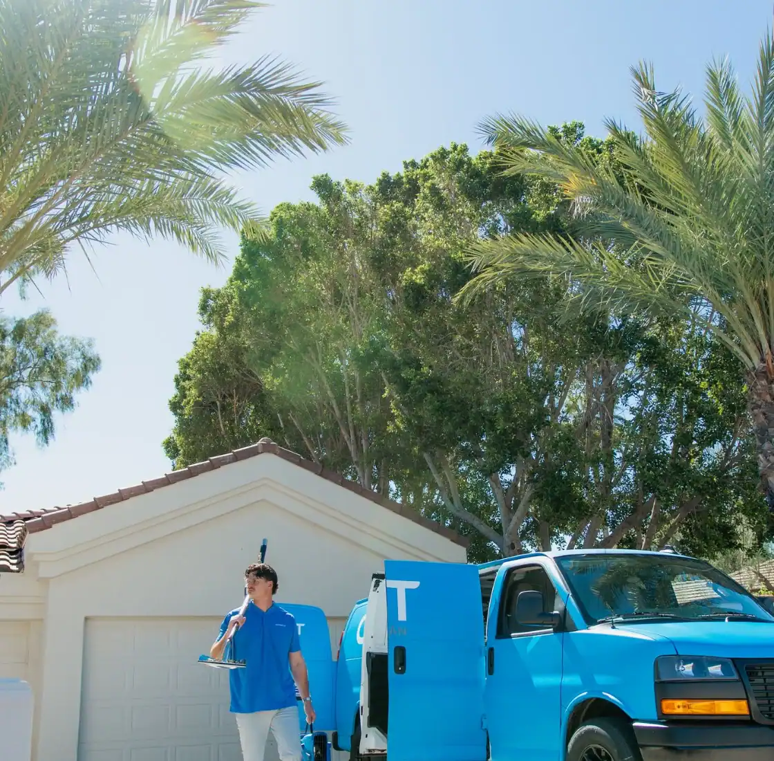 Coconut Cleaning technician carrying an extraction wand beside the service van