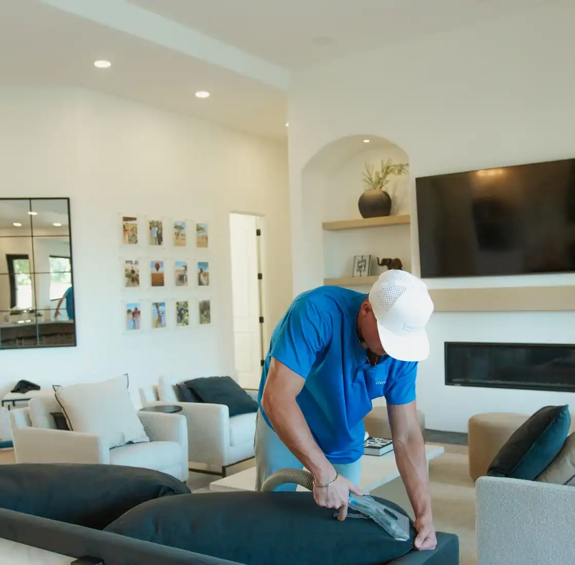 Technician cleaning upholstery in a bright open living room